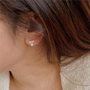 Close-up of elegant white pearl and silver zircon earrings worn by a female model