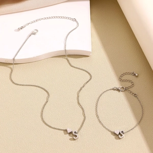 Détail du pendentif cœur et lettre S sur un ensemble de collier et bracelet minimaliste