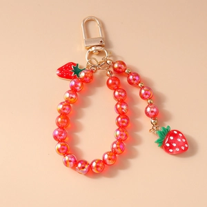 Detailed shot of beaded keychain featuring strawberry charms and golden metal clasp