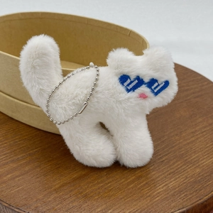 Plush white cat charm with blue heart sunglasses and silver bead chain on a wooden tray