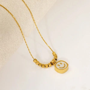 Detailed close-up of a gold-plated smile necklace with square pendant and metallic beads