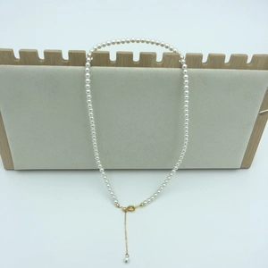 Detailed view of white round pearl necklace with 14k gold adjustable chain and lobster clasp