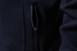 Detail of waffle knit fabric on navy jacket with a vertical metal zipper pocket