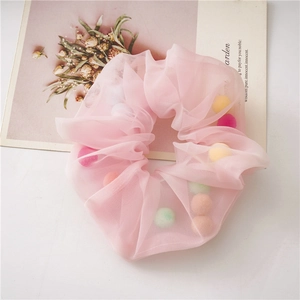 Detail of pink mesh scrunchie filled with colorful balls on a fresh white desk