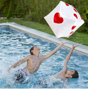 Foto di bambini che giocano con un dado gonfiabile bianco a cuori in una piscina aperta