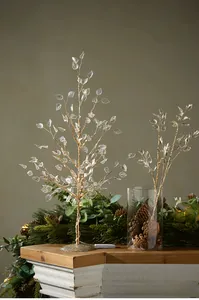 Macro shot of gold LED Christmas branch decorations with frosted leaves on a wooden mantle