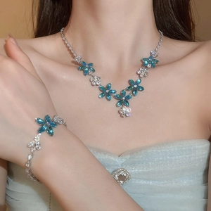 Gros plan d'un mannequin portant l'ensemble collier et bracelet fleur zircon bleu