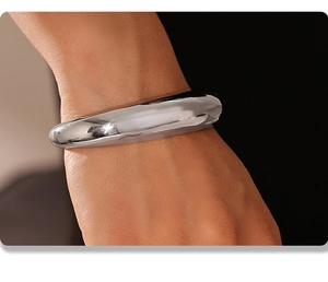 Macro shot of polished silver stainless steel crescent cuff bracelet on wrist