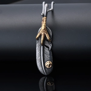 Detail of vintage silver feather pendant with gold bird claw and circular emblem