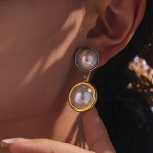 Elegant two-tone stainless steel pearl drop earrings for women worn by a model