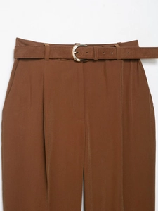 Détail d'un pantalon marron à taille haute avec ceinture assortie et boucle dorée ovale