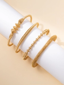 Close-up of four-piece gold titanium steel bracelets with woven and spiral textures