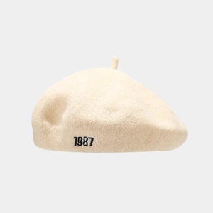 Detailed close-up of the 1987 embroidery on a cream wool blend beret hat for women