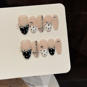 Unghie finte fatte a mano rosa nudo con pois neri e decorazioni a fiocco argento