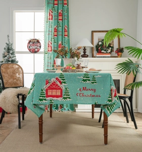 Close-up of Christmas tablecloth featuring red house and tree prints on cotton linen fabric