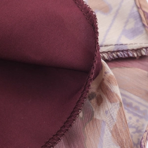 Detail of bohemian paisley print chiffon and burgundy fabric with fine stitching