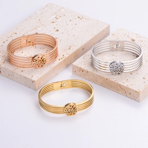 Three-tone hollow stainless steel bangles with crystal tree design on travertine stone