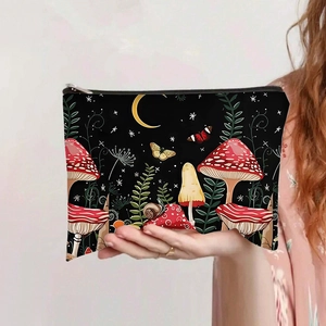 Canvas makeup bag with forest mushroom print and zipper closure held by hand
