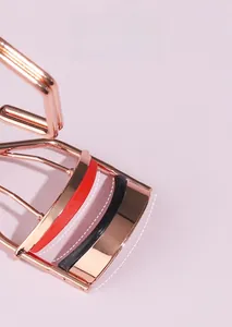Dettaglio macro del piegaciglia oro rosa con design grandangolo e cuscinetti bicolore