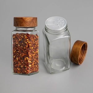 Square glass spice jar with acacia wood lid and shaker lid set on a grey background