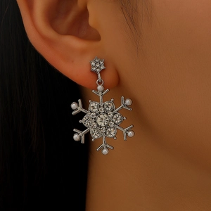 Close-up of sparkling snowflake earrings with pearls and crystals worn on model