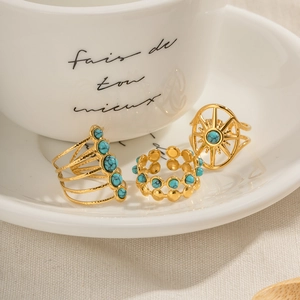 Bohemian gold rings set with blue stone and floral patterns in ceramic tray