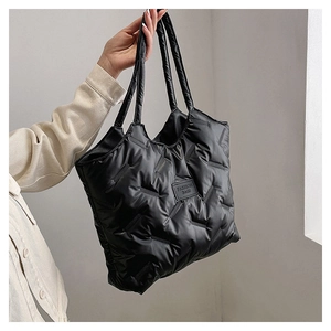 Detail of black quilted puffer tote bag with fashion leather patch and soft padded handle