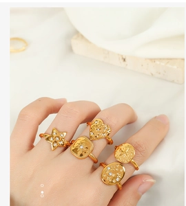 Close-up of a hand wearing five gold geometric rings with star and heart zircon details