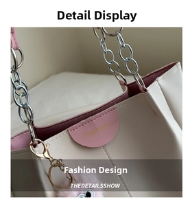 Dettaglio della borsa tote crema con bordo rosa, logo dorato e ciondolo di peluche