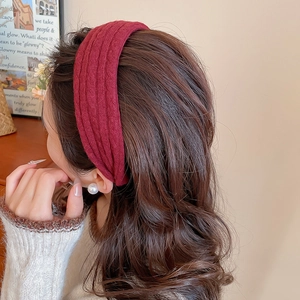 Détail d'un large serre-tête rouge en maille texturée sur des cheveux bouclés bruns