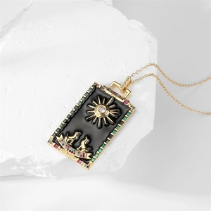 Detail of tarot card necklace with sun and enamel pendant on textured white stone