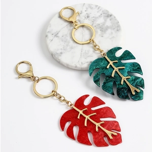 Detail of red and green monstera leaf keychains with glitter resin and gold metal veins