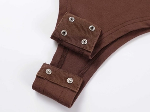 Close-up of four silver metal snap buttons on the crotch of a brown cotton bodysuit