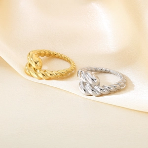 Detailed view of gold and silver twisted cable rings on beige silk background