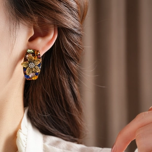 Close-up of vintage floral earrings with colorful gemstones and pearls on ear