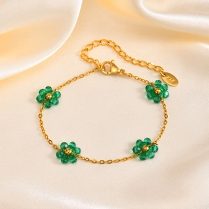 Close-up of golden flower bracelet with green crystal beads and a K18 metal tag