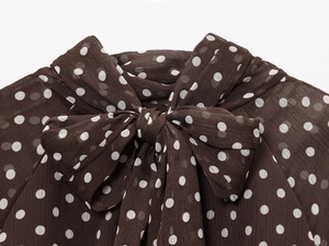 Detailed close-up of brown chiffon shirt featuring white polka dots and elegant bow tie neck
