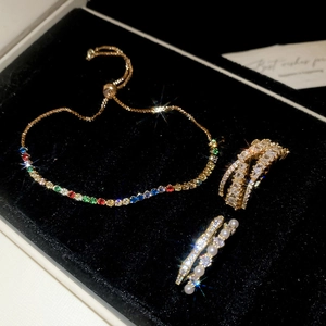 Detail of luxury gold jewelry set with colored gemstones and pearls on black velvet