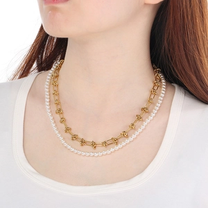 Close-up of double-layered gold chain and white baroque pearl necklace on female model