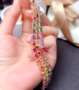 Rainbow gemstone bracelets in rose gold, white gold, and yellow gold plating shown handheld
