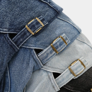 Detail view of denim flat caps featuring metal adjustable buckles and precise stitching