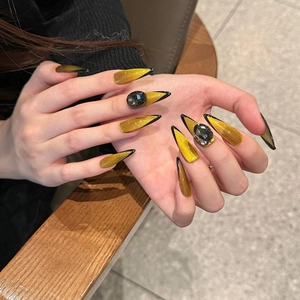 Handmade stiletto press-on nails with golden cat-eye effect and black edging accents