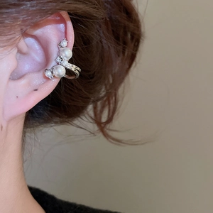 Detail view of model wearing a silver pearl ear cuff with zircon accents for non-pierced ears