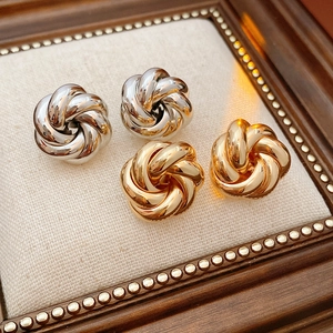 Detail of twisted metal knot earrings in gold and silver finish on display stand