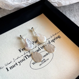 Macro shot of baroque pearl drop earrings with elegant silver metallic pendant detail
