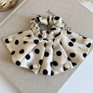 Détail d'un chouchou en satin à pois avec perles élégantes sur la couverture d'un livre