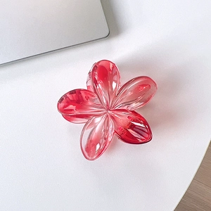Macro shot of transparent red gradient frangipani hair claw with sturdy metal spring