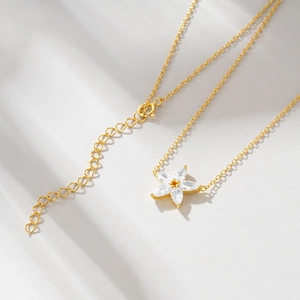 Detail of 18K gold star flower necklace featuring sparkling zircon stones on stone surface