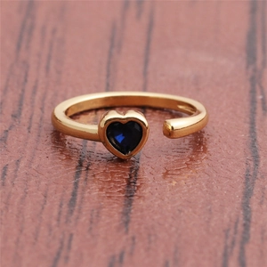Detailed macro view of a golden open ring featuring a blue heart-shaped gemstone