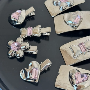 Macro detail of silver hair clips with pink rhinestones in heart and flower shapes